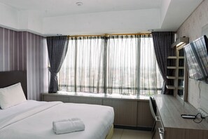 Relax in a spacious room with a large bed, flat-screen TV, and sheer curtains.