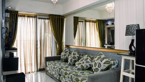 A living room with a sofa, a television, and a large mirror. - Chic and Cozy 1BR Apartment at H Residence near MT Haryono (Jakarta)