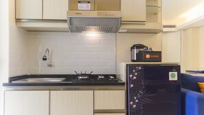 A compact kitchen with a stove, sink, and a refrigerator. - Nice and Comfy 2BR Bassura City Apartment near Mall (Jakarta)