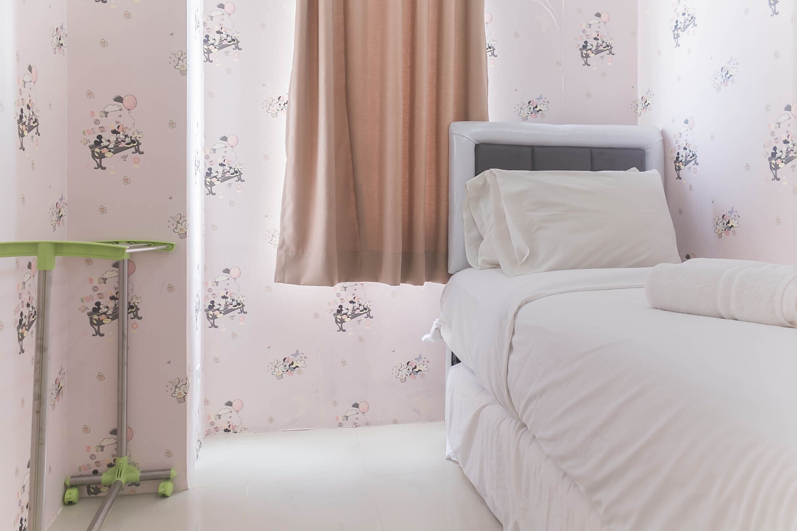 A bedroom with a bed, a window with curtains, and a green cleaning cart.