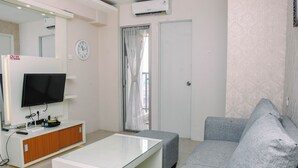 Una sala de estar moderna con un televisor de pantalla plana, una mesa de centro de vidrio, sofás grises y un mueble blanco.
