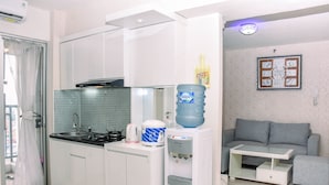 Una cocina moderna con armarios blancos, dispensador de agua y cafetera.