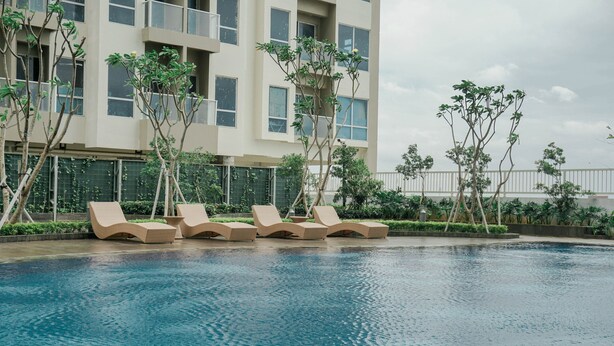 Ein Swimmingpool mit Liegestühlen und ein Gebäude mit mehreren Fenstern im Hintergrund.