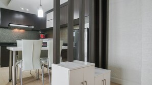 A modern kitchen with dark cabinetry, a white countertop, and stainless steel chairs. - Best Location 2BR at The Wave Kuningan Apartment (Jakarta)