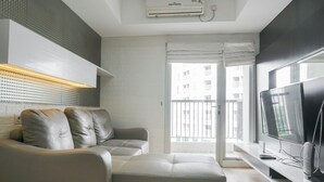 A modern living room with a sofa, a flat-screen TV, and a built-in sound system. - Best Location 2BR at The Wave Kuningan Apartment (Jakarta)