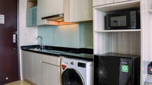 Une cuisine compacte équipée d’un lave-linge, d’un four à micro-ondes et d’un réfrigérateur de la marque Sharp.