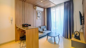 A modern living room with a sofa, a small dining table, and a kitchen area with a bar counter. - Fabulous 1BR Apartment at The Newton Ciputra World 2 (Jakarta)