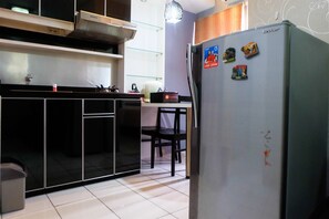 Een koelkast, een kookplaat, kookgerei, borden en bestek