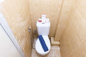 A small bathroom with a toilet, a towel, and a shower.