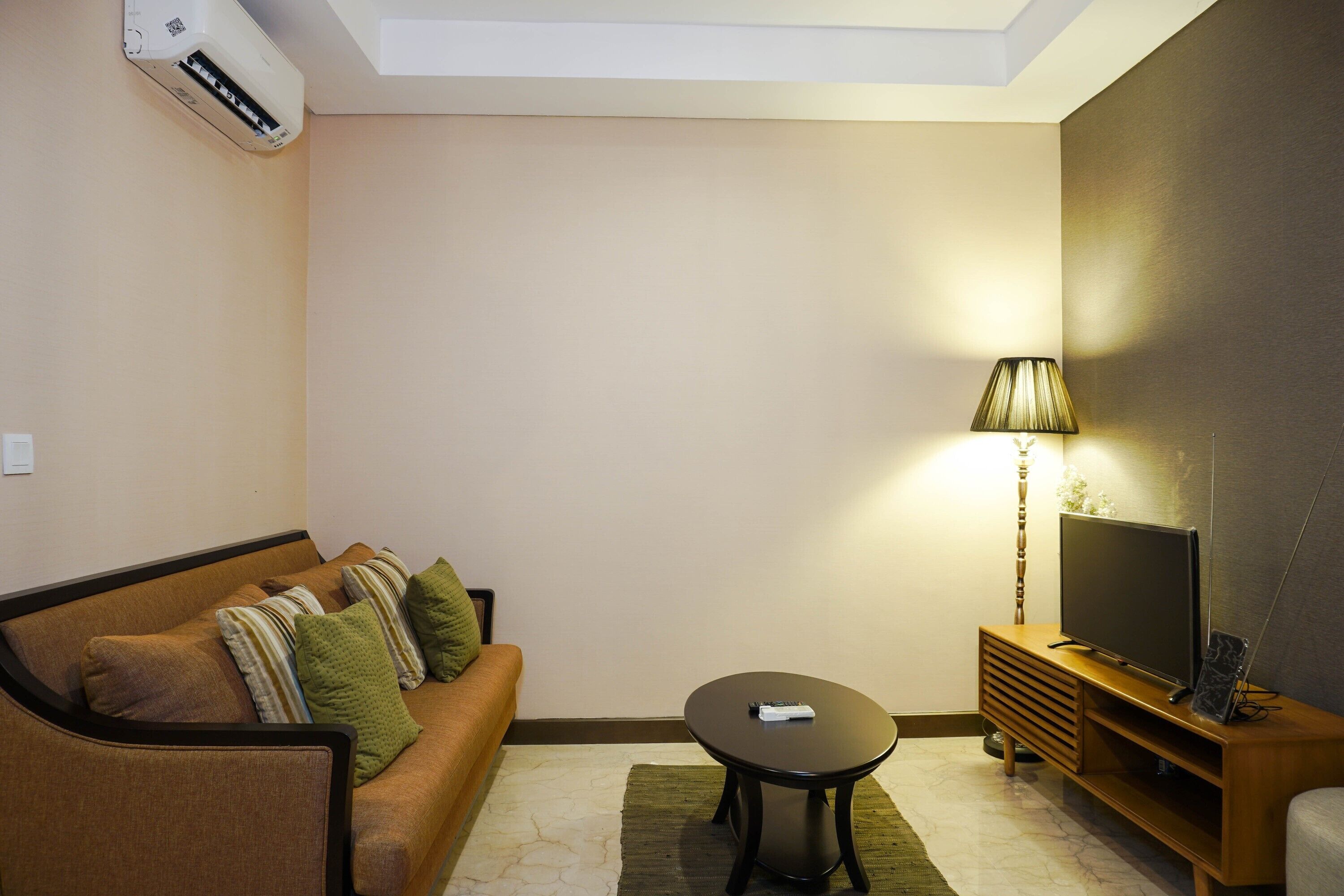 A modern living room with a sofa, a coffee table, a TV on a wooden stand, and a lamp.