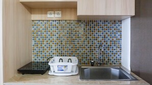 Una cocina con salpicadero de azulejos, un lavamanos de acero inoxidable y una encimera con escurreplatos blanco.