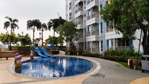 Una piscina con toboganes, rodeada por un edificio con balcones y palmeras.