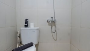 Un baño pequeño y limpio con inodoro, ducha y una toalla sobre el inodoro.