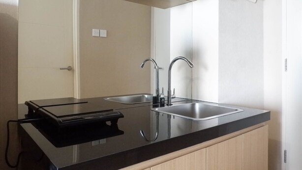 Una cocina moderna con dos lavamanos de acero inoxidable, encimera negra y armarios de madera.
