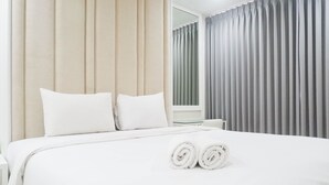 A hotel room with a neatly made bed, a bedside table, and a window with curtains. - Spacious 1BR Apartment at Praxis (Surabaya)