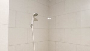 Une douche avec un pommeau de douche amovible dans une salle de bain carrelée.