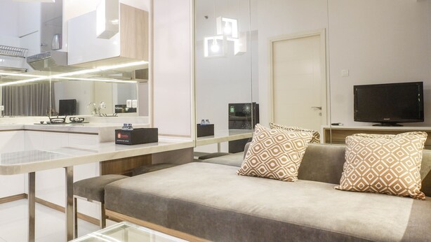 Une chambre d’hôtel moderne équipée d’un canapé, d’une télévision, d’un miroir et d’un coin cuisine.
