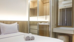 Une chambre d’hôtel avec un lit, une armoire, un miroir et une petite table de chevet.