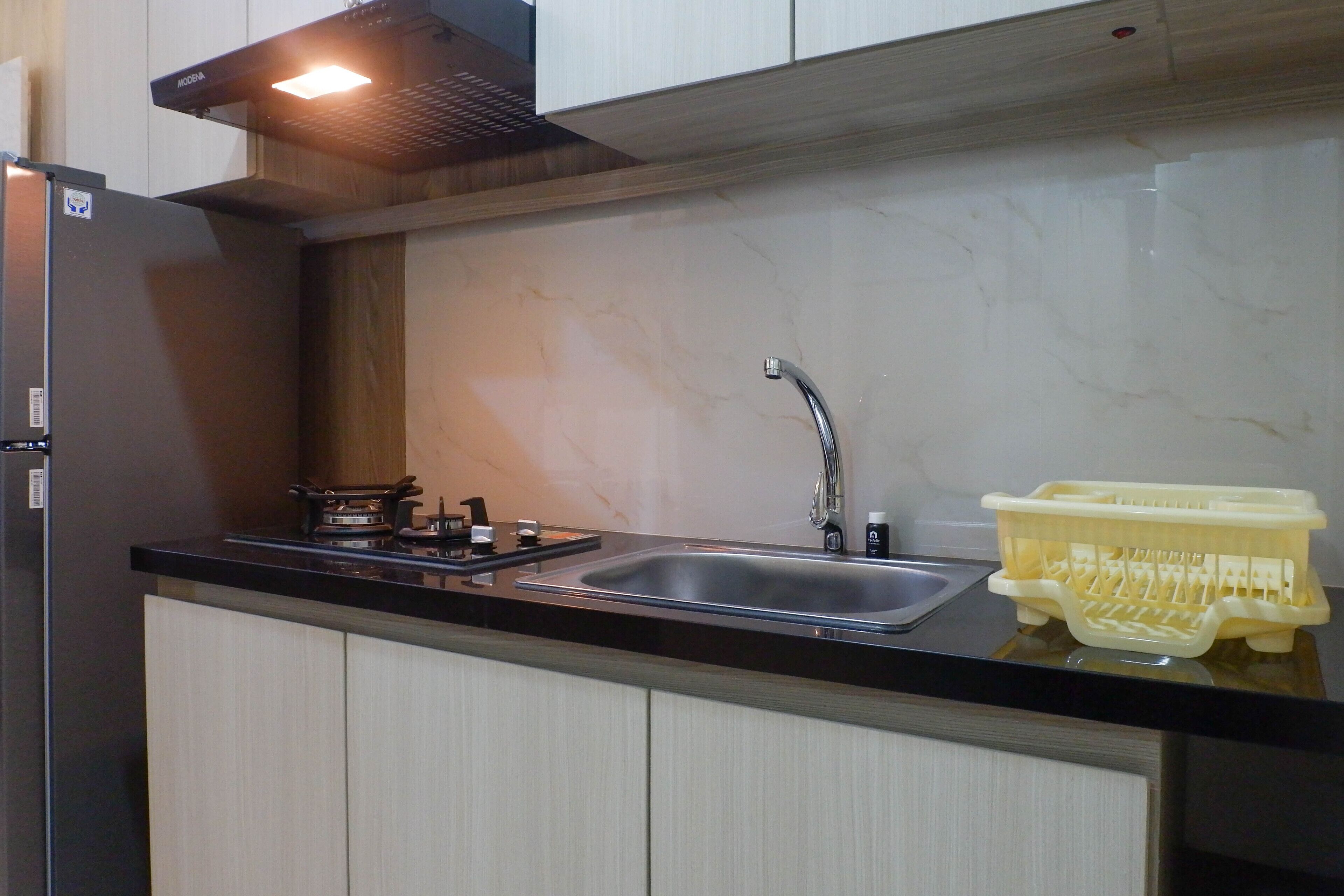 A kitchen with a black countertop, stainless steel sink, and a yellow dish rack.