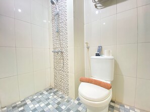 Une salle de bain avec des toilettes, une douche et un sol carrelé.