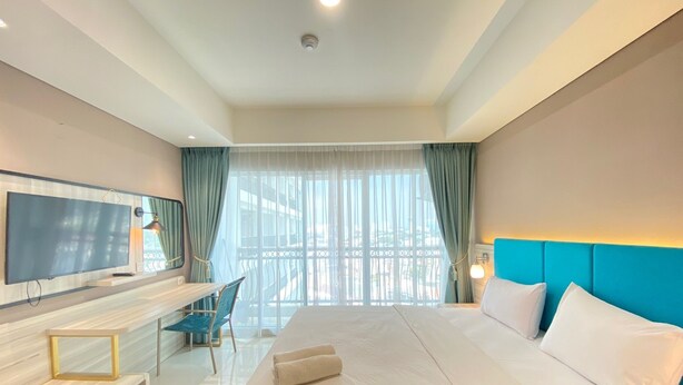 Une chambre d’hôtel avec un grand lit, une télévision, un bureau avec une chaise et une vue sur l’extérieur par la fenêtre.