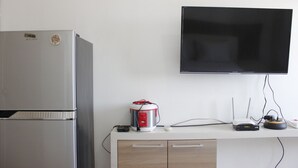 Eine Küche mit Kühlschrank, Mikrowelle, Reiskocher und einem flachbildschirmigen Fernseher an der Wand.