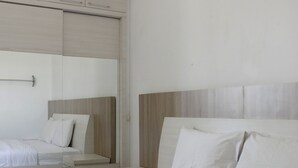 Ein modernes Hotelzimmer mit einem großen Bett, einem kleineren Bett und einem begehbaren Kleiderschrank.