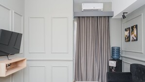 A modern living room with a flat-screen TV, a water dispenser, and a sofa. - Comfortable and Homey 2BR Apartment at M-Town Residence (Gading Serpong)