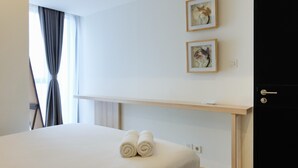 Ein Hotelzimmer mit einem Bett, zwei gerahmten Kunstwerken an der Wand, einem Nachttisch und einer Tür.