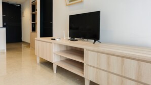 Ein modernes Hotelzimmer mit einem Holzkonsolentisch, einem Flachbildfernseher und integrierten Regalen.