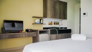Une chambre d’hôtel comprenant un lit, une télévision, une petite kitchenette et une salle de bain.