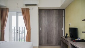 Une chambre d’hôtel équipée d’un lit, d’un bureau avec un ordinateur, d’un climatiseur et d’une porte coulissante.