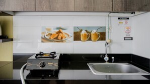 Une cuisine équipée d’une cuisinière à gaz, d’un évier et d’un crédence carrelée ornée d’images de produits alimentaires.