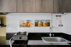 A kitchen with a gas stove, a sink, and a tiled backsplash with images of food.