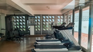 Un gimnasio con cintas de correr, equipamiento de ejercicio y amplios ventanales que ofrecen vistas al exterior.
