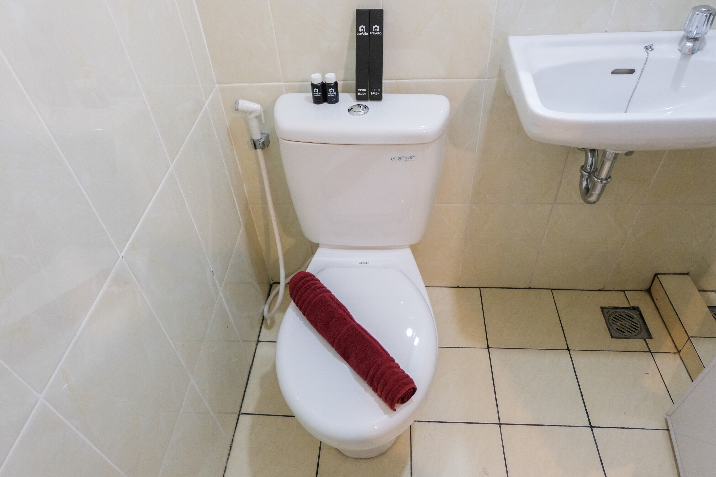 A toilet with a red towel on it, a bidet, and a sink.
