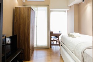 Un dormitorio con una cama, un armario de madera, un escritorio y una televisión.