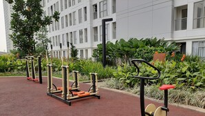 Outdoor exercise equipment in a landscaped area with a building in the background. - Studio Room Apartment at M-Town Residence near Summarecon Mall Serpong (Gading Serpong)
