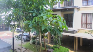 A residential building with a balcony, a parking area, and a well-maintained garden.