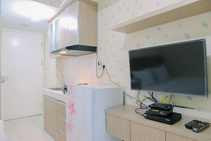 Una cocina moderna con horno empotrado, microondas y televisor de pantalla plana montado en la pared.