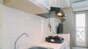 A modern kitchen with a stainless steel sink, a gas stove, and a built-in oven. - Modern Furnished Studio at Springlake Summarecon Bekasi Apartment (Bekasi)