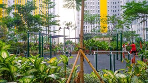 An outdoor gym area with exercise equipment, surrounded by lush greenery and tall buildings in the background. - Modern Furnished Studio at Springlake Summarecon Bekasi Apartment (Bekasi)
