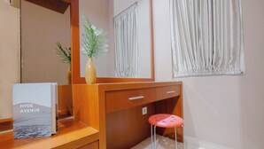 A hotel room with a wooden desk, a small stool, a mirror, a potted plant, and a sign reading "Hyde Avenue". - Modern 2BR Apartment for 4 Pax at Springlake Summarecon (Bekasi)