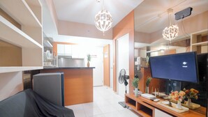 A modern living room with a TV, entertainment unit, and a covered sofa. - Modern 2BR Apartment for 4 Pax at Springlake Summarecon (Bekasi)