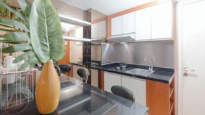A modern kitchen with a black countertop, stainless steel appliances, and white cabinets. - Modern 2BR Apartment for 4 Pax at Springlake Summarecon (Bekasi)