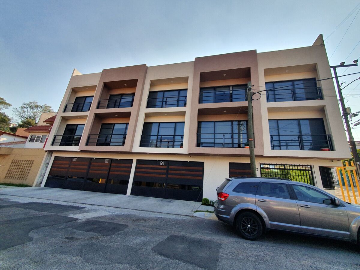 A multi-story building with a modern architectural design, featuring a garage with a car parked in front.