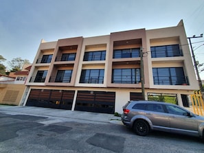 En bygning med flere etager og moderne arkitektur, med en garage foran hvor en bil er parkeret.