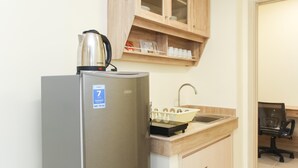 A compact kitchen with a stainless steel refrigerator, a kettle, and a sink with a modern faucet. - Spacious and Well Appointed 2BR at Meikarta Apartment (Cikarang)