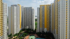 A high-rise residential building complex with multiple apartment buildings, a central courtyard with a swimming pool, and surrounding greenery. - Modern and Full Parquette @ Studio Springlake Summarecon Apartment (Bekasi)