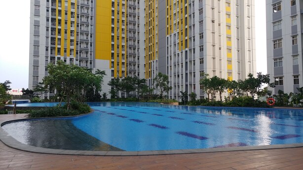 A residential building with a swimming pool surrounded by greenery. - Modern and Full Parquette @ Studio Springlake Summarecon Apartment (Bekasi)